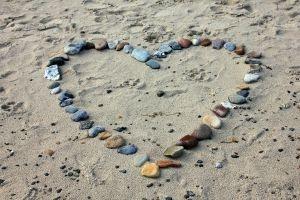 Ein Herz aus Steinen am Strand, das vielleicht ein Paar gestaltet hat, das keinen Streit im Urlaub hat.